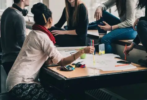 Fünf Menschen sitzen bei einem Meeting in lockerer Stimmung
